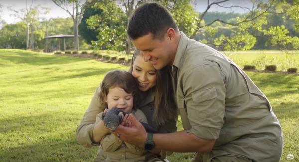 Bindi Irwin and husband Chandler holding their baby daughter Grace with saddened expressions