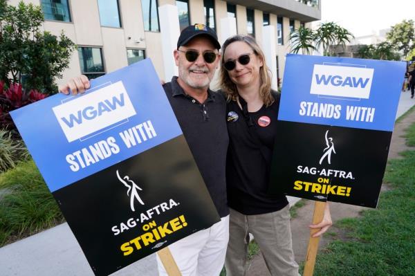 Writers Matthew Weiner, left, and Semi Chellas carry signs on the picket line outside Netflix on Sep. 27, 2023, in Los Angeles.